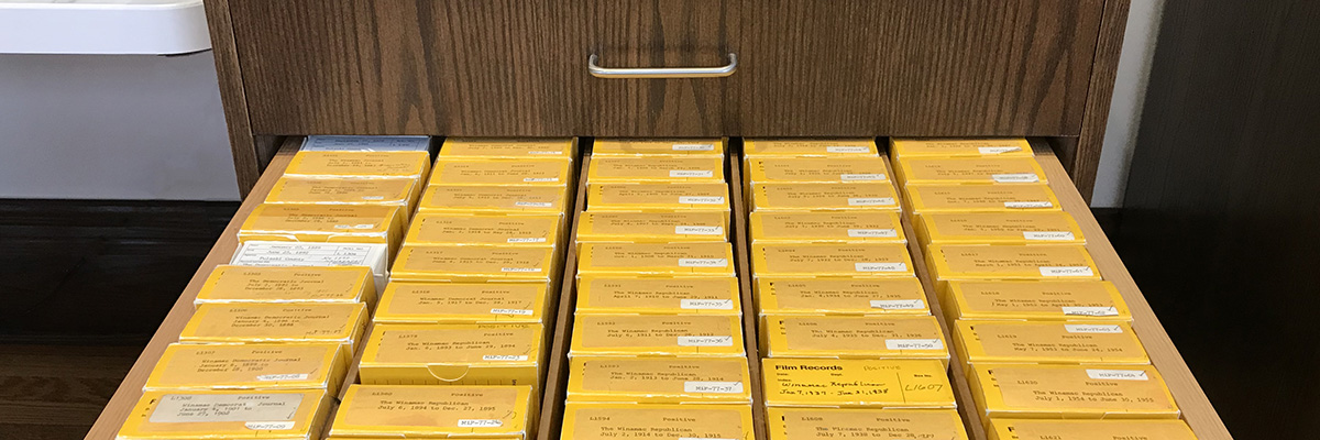 An open drawer in one of the library's microfilm cabinets filled with boxes of rolls of microfilm.