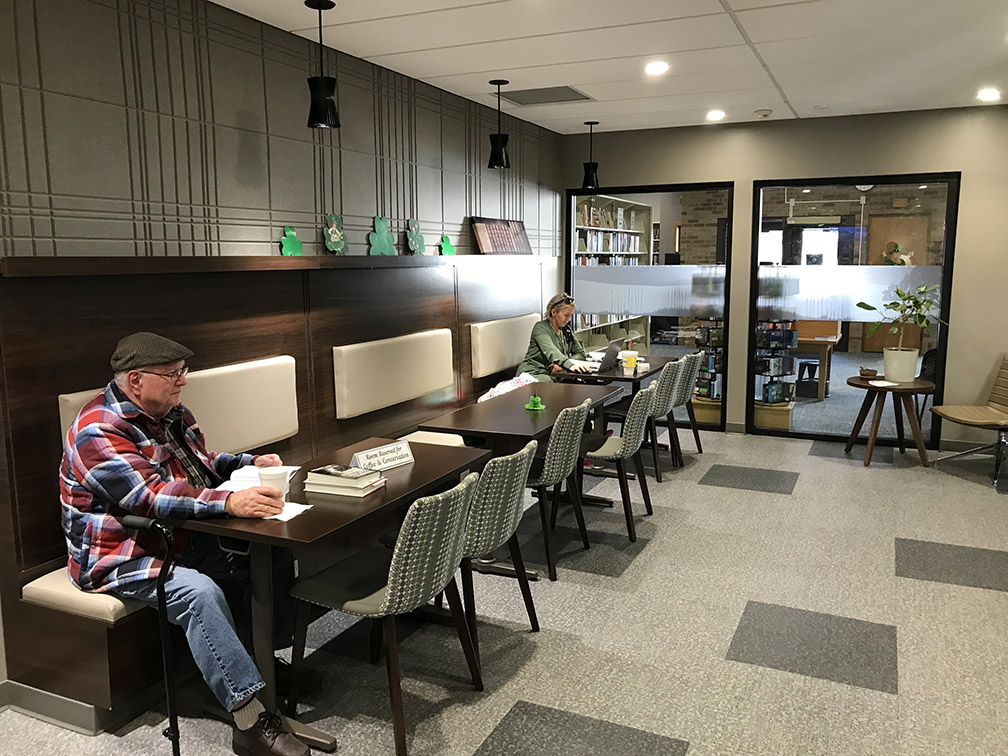 A row of tables in the library's Café/Lounge, featuring bench seating on one side and chairs on the other.