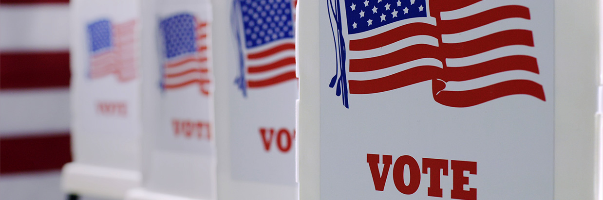 row of voting booths with American flag images at polling station during American election