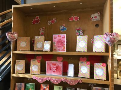 A bookshelf displaying Valentine's Day decorations and books covered in wrapping paper.