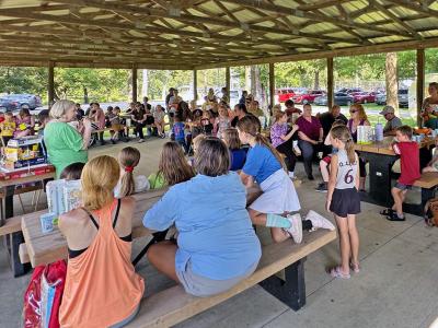 A crowd of children and their families gathered under the pavilion next to the Artesian Well at the library's 2025 Summer Reading Party.