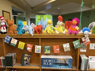 several stuff animals of Dr. Seuss characters and a banner featuring many Dr. Seuss book covers in the PCPL Children's Area