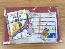 PCPL's Kindergarten Readiness Kit: a large, flat plastic envelope containing children's books, pencil, crayons, calendars, and other papers.