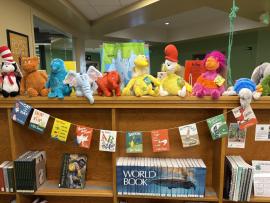 several stuff animals of Dr. Seuss characters and a banner featuring many Dr. Seuss book covers in the PCPL Children's Area