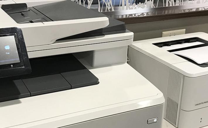 Black & white and color printers printing documents at the library.